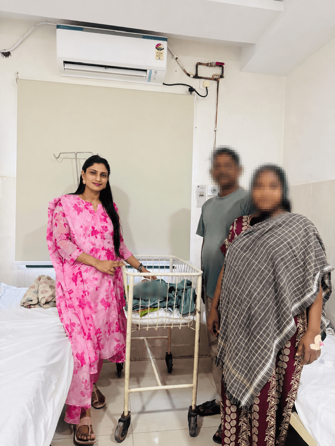 Dr. Dedeepya with an anonymized family beside a maternity bassinet